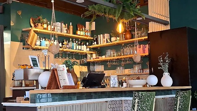 The bar at MidDay + Good Impressions in Dayton, Ohio, with espresso equipment below a shelf of spirits