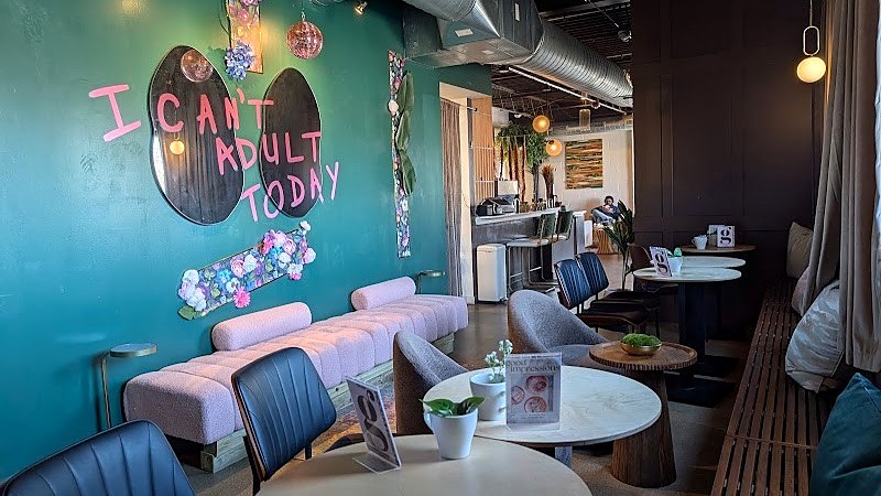 The lounge at MidDay + Good Impressions in Dayton, with a mural reading I can't adult today above a pink banquette